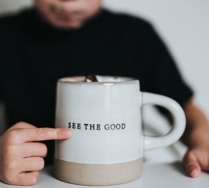 man in black long sleeve shirt holding white ceramic mug