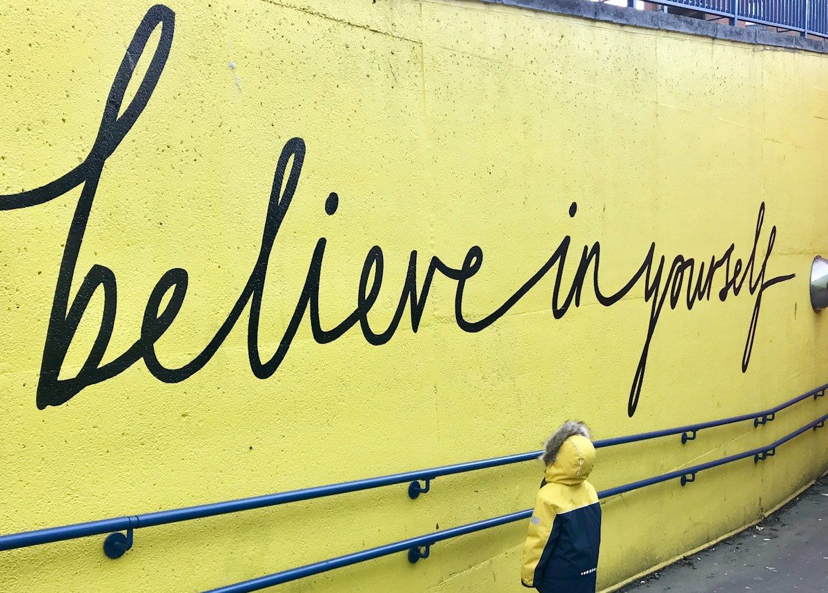 toddler looking at believe in yourself graffiti